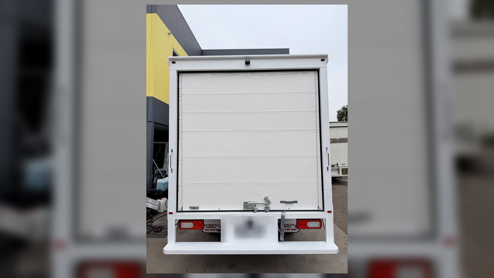 Rear roller door and tailgate on white Isuzu box truck